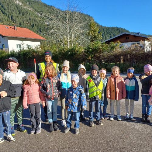 Alle Kinder und die Polizistin stehen als Gruppe zusammen und lächeln in die Kamera