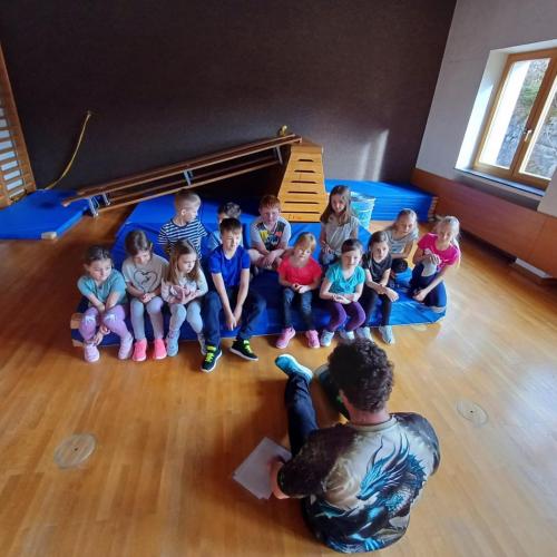 Kinder sitzen im Turnsaal auf Matte