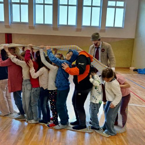 Ein Clown macht eine Teambuilding-Übung mit Kindern in einem Turnsaal