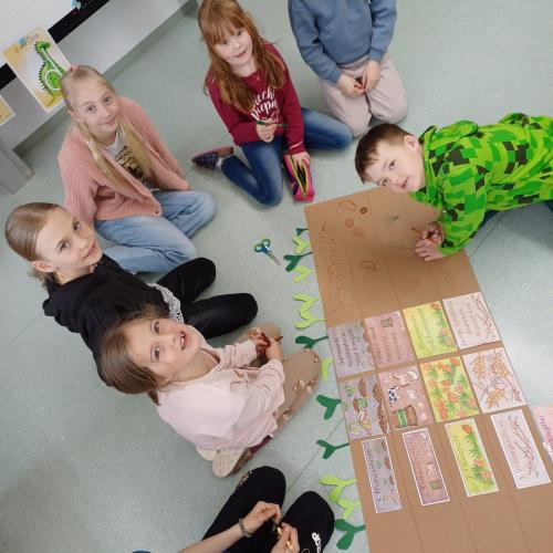 Schulkinder planen mittels Plakat Schichten eines Hochbeets