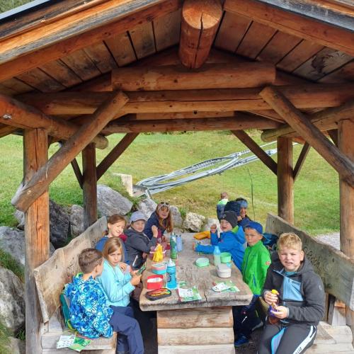 Kinder essen ihre Jause auf einem Rastplatz auf Holz