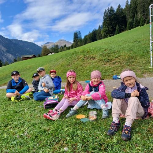 Gruppenfoto mehrer Kinder bei Jause essen sitzend im Gras