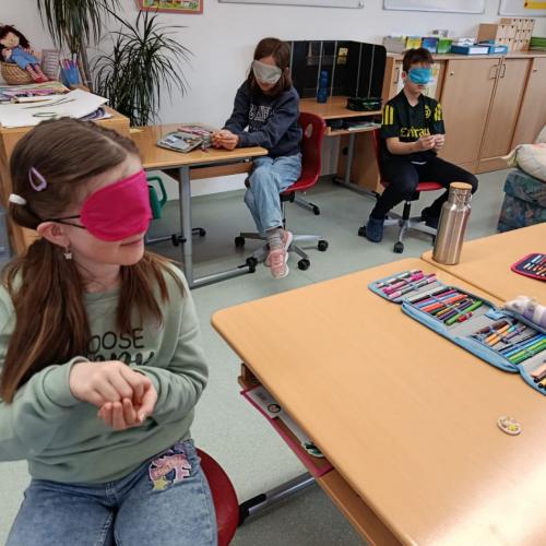 Kind mit pinker Augenbinde in der Schule auf seinem Platz