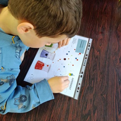 Ein Kind mischt Lebensmittelfarbe auf einer Folie