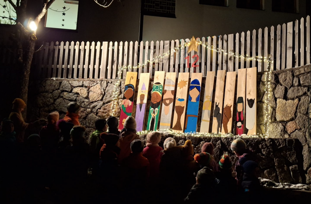 Bretterinstallation, die die Krippe darstellen, Kinder stehen davor, es ist dunkel