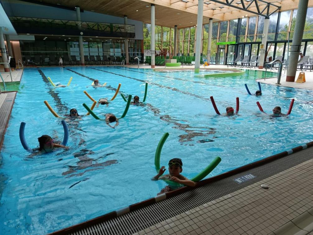 Kinder mit Schwimmnudeln im Wasser im Hallenbad