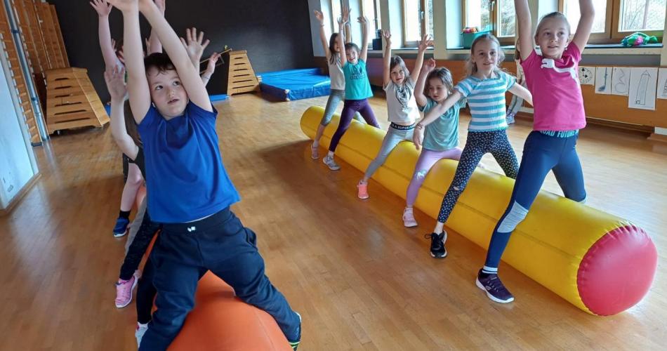 Kinder bewegen sich im Turnsaal auf zwei großen Luftschlangen.