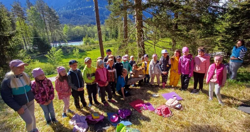 Schülergruppe steht mit Naturpädagoginnen im Wald
