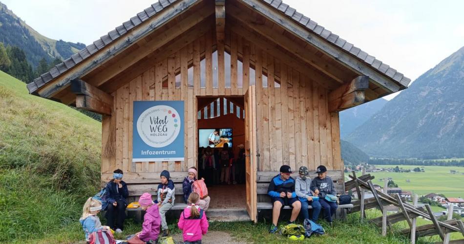 Kinder sitzen vor einer Hütte