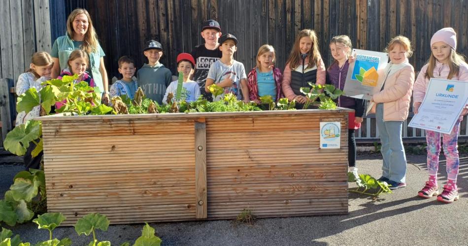Gruppenfoto einer Schulklasse vor einem Hochbeet