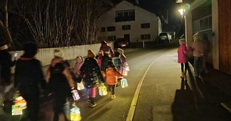 Kinder ziehen mit ihren Laternen in der Dunkelheit durch die Straßen