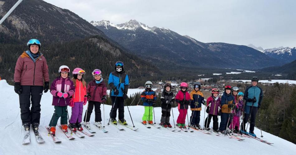 Gruppe von Schülern in einer Reihe mit Schiausrüstung am Schihang