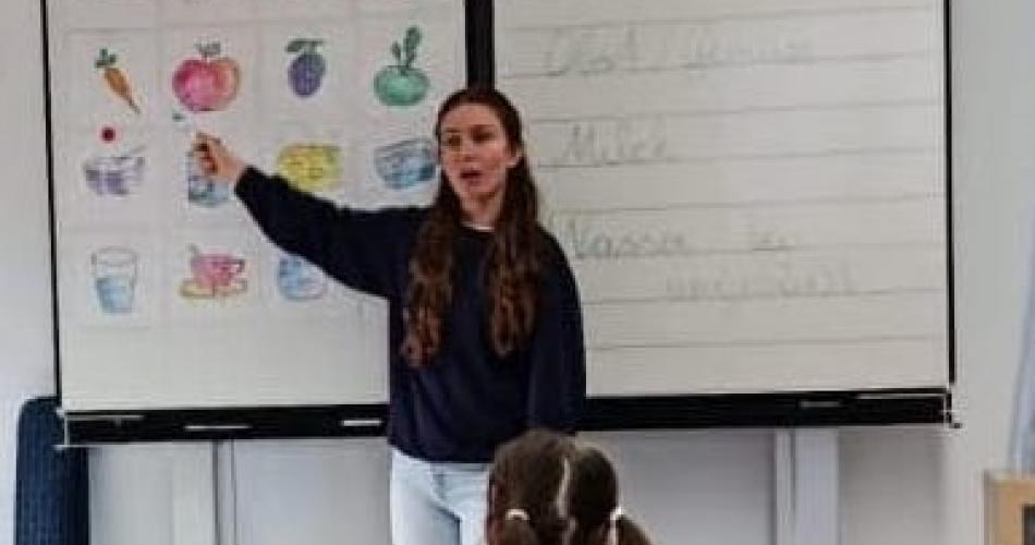 Vortragende vor weißer Tafel auf Bilder zeigend