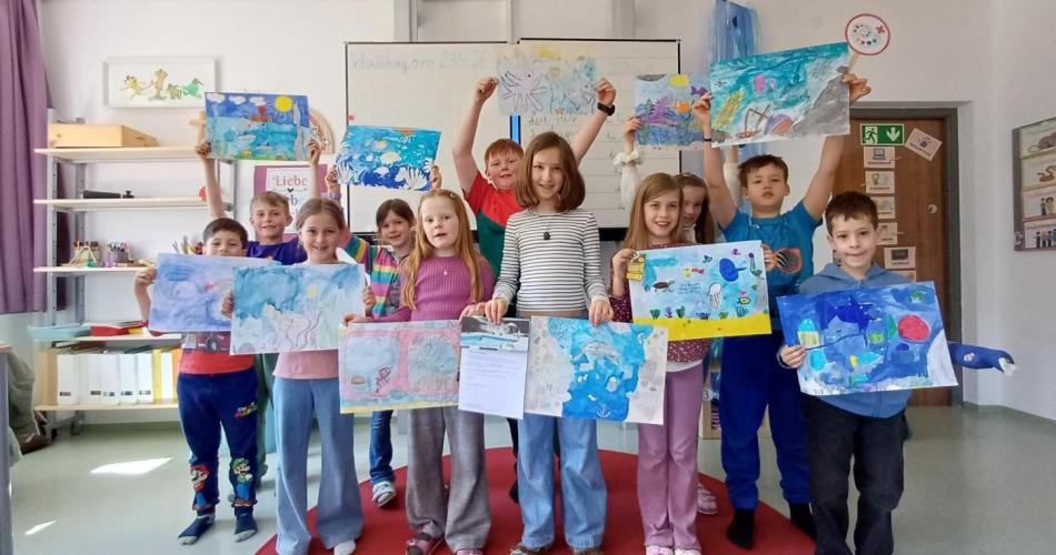 Gruppe von Kinder mit Zeichnungen in der Hand in der Schulklasse
