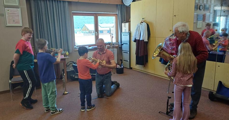 Kinder in einem Problelokal, probieren verschiedene Blasinstrumente aus