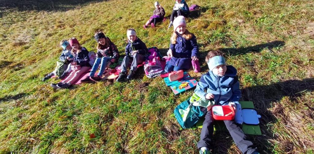 Kinder sitzen auf der Wiese und jausnen.