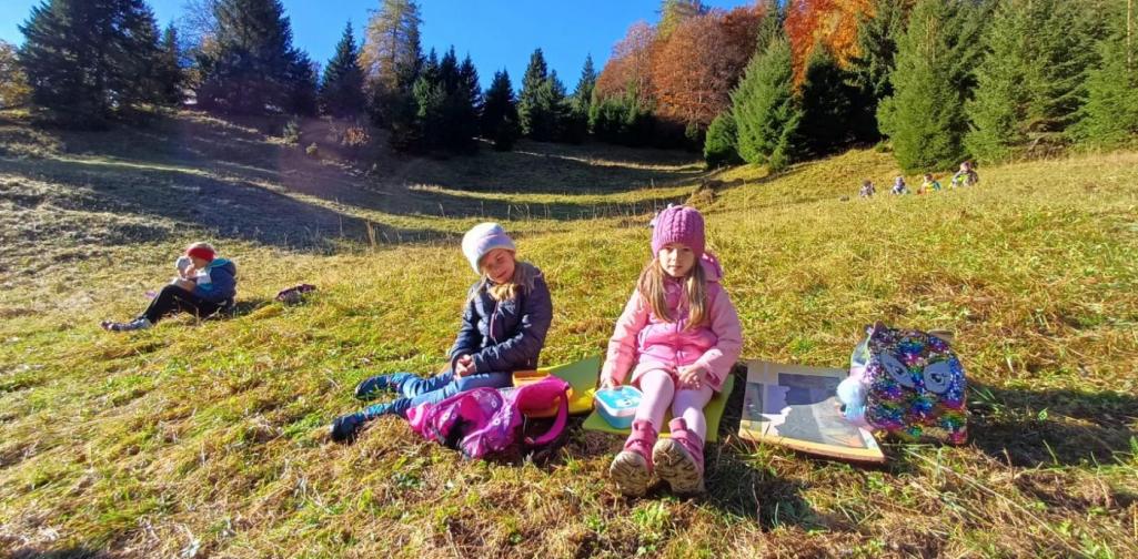 Kinder sitzen auf der Wiese und Jausnen.